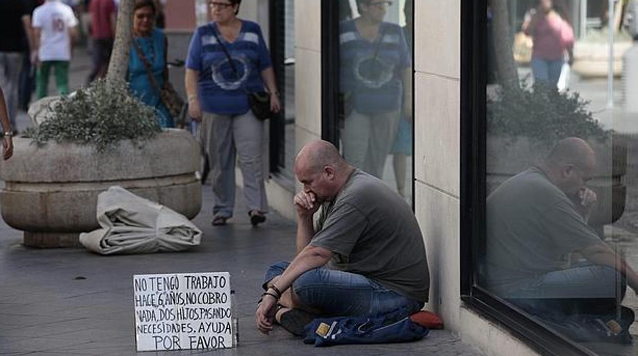 Una persona pide dinero en una calle de Sevilla