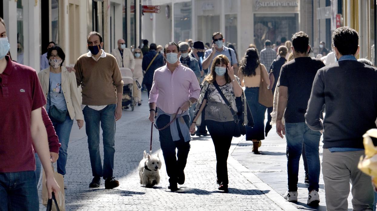 Ciudadanos paseando por una calle comercial de Sevilla manteniendo las distancias y con mascarillas