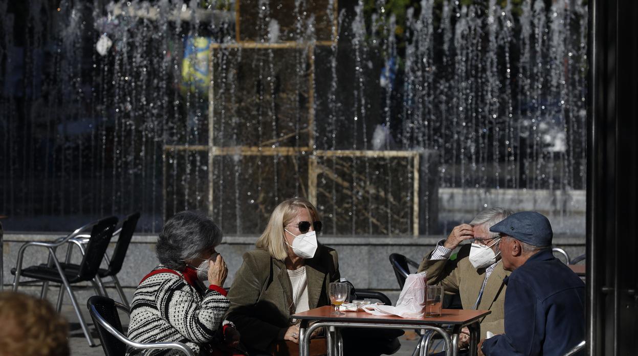 Varias personas, sentadas en una mesa al sol en una terraza de Gran Capitán