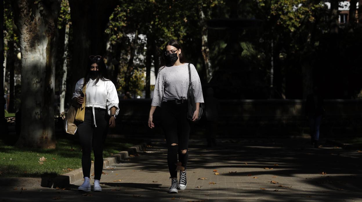 Dos jóvenes pasean por un parque de Córdoba en noviembre