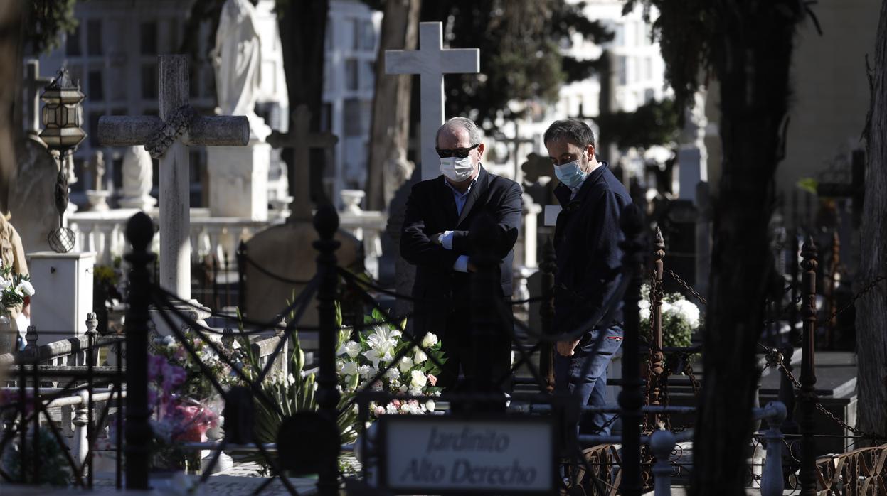 Dos hombres visitan una tumba en el cementerio de la Salud de Córdoba