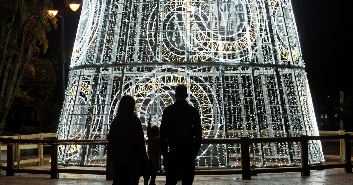 Una familia observa un árbol navideño en la Plaza de la Marina de Málaga