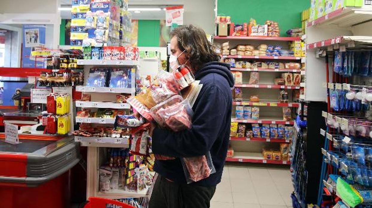 Un hombre realiza la compra en un sepermecado con la mascarilla puesta