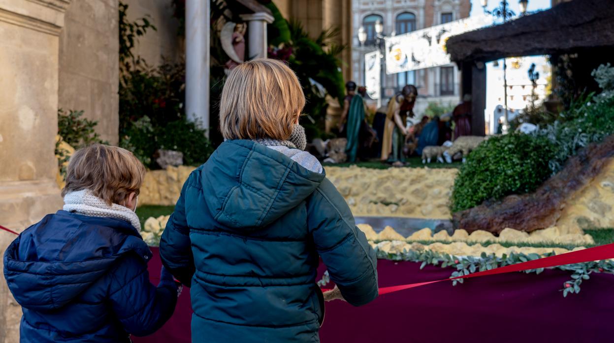 Dos niños contemplan un belén instalado en el Ayuntamiento de Sevilla