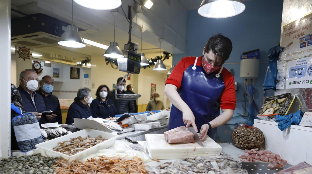 Un hombre corta pescado para uno de sus clientes en el mercado del Marrubial