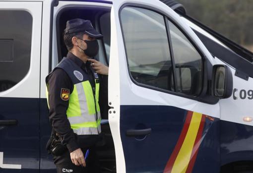 Un agente de la Policía junto a un vehículo del Cuerpo