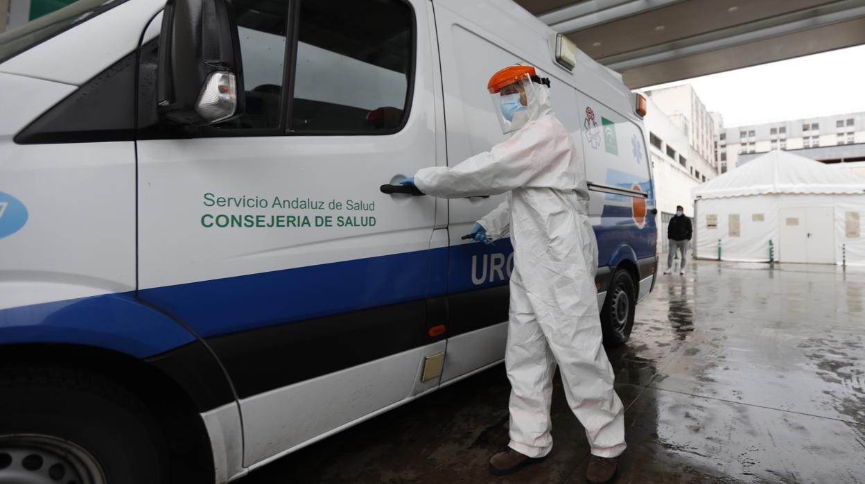 Un sanitario en su ambulancia con un traje EPI en la puerta de Urgencias del Reina Sofía