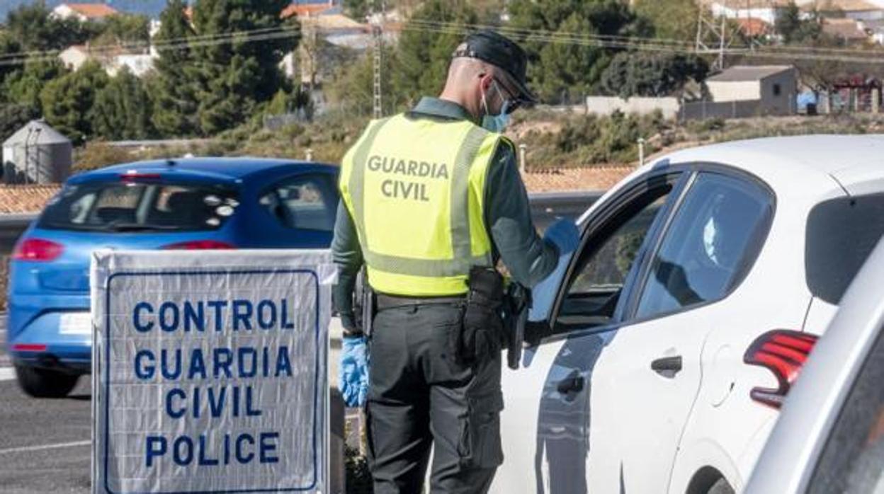 Un agente de la Guardia Civil para a un coche en un control debido al cierre perimetral por el coronavirus