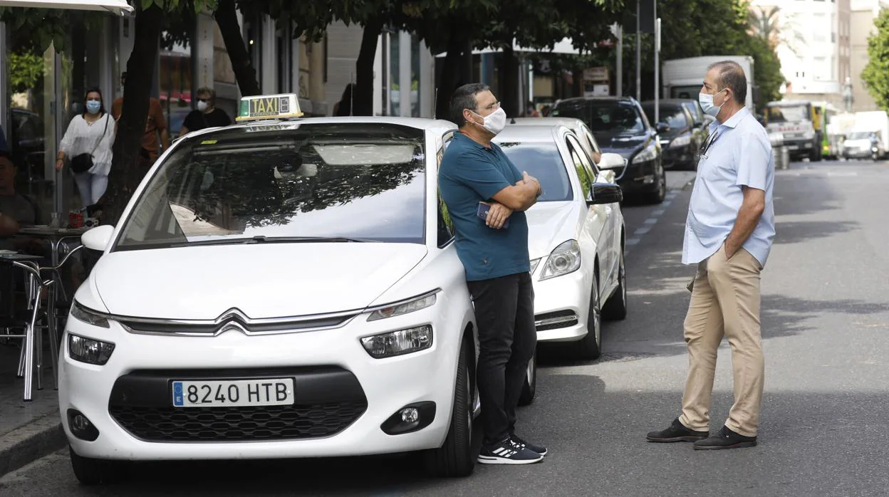 Dos taxistas en Córdoba junto a sus vehículos
