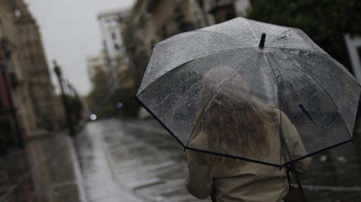 Una joven se protege de la lluvia con su parguas