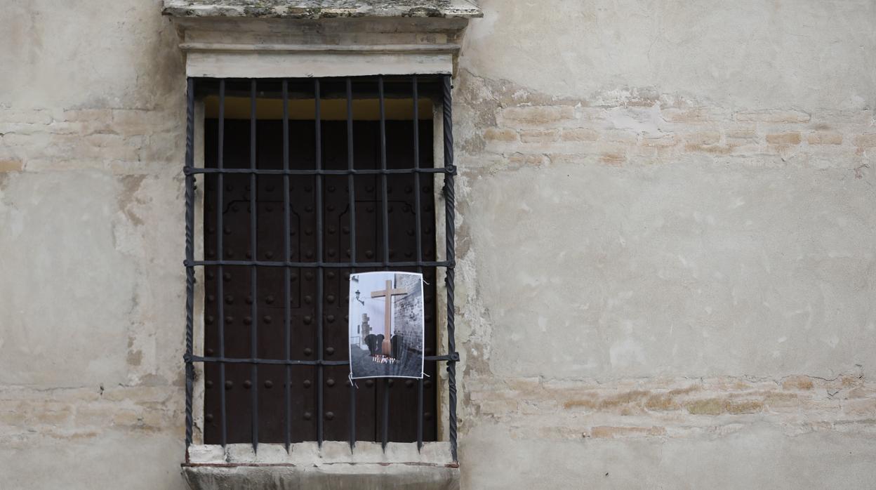 Fotografía de la cruz retirada en una ventana con reja de Aguilar de la Frontera