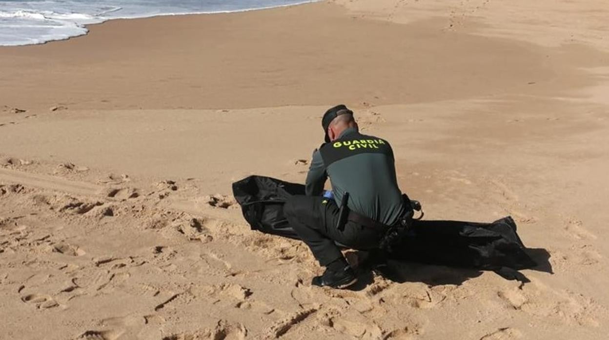 Un agente de la Guardia Civil junto a un cadáver en la playa en una imagen de archivo