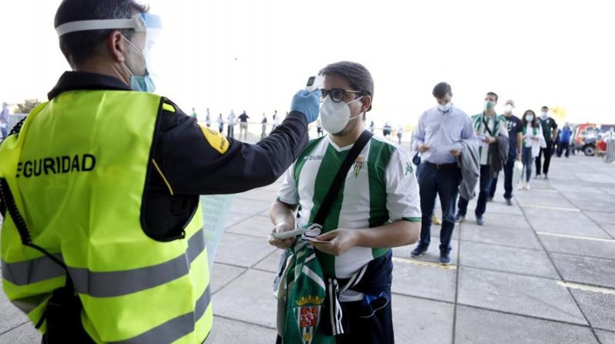 Un operario toma la temperatura a un aficionado antes de entrar al estadio