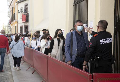 Un vigilante toma la temperatura a los que van a entrar en la iglesia de Santiago