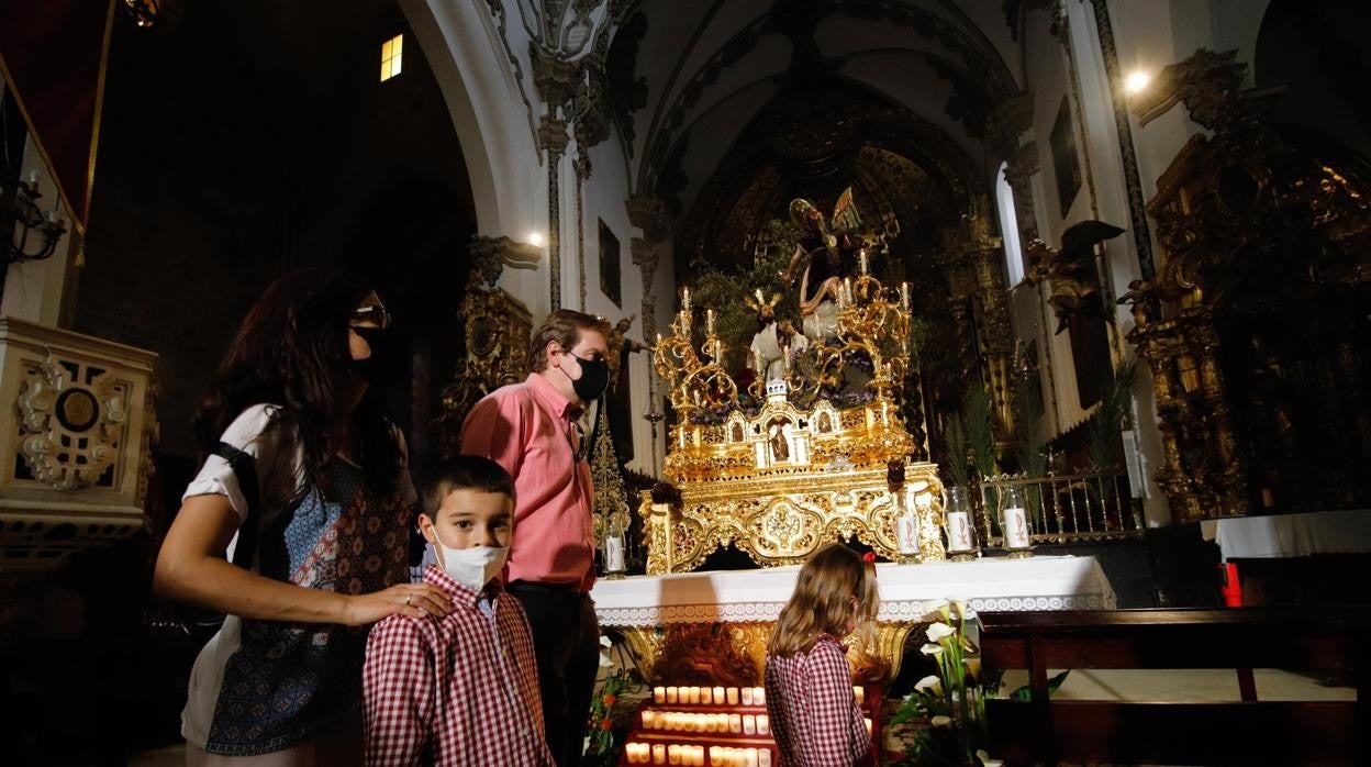 Una familia pasa ante el paso de la Oración en el Huerto el Domingo de Ramos