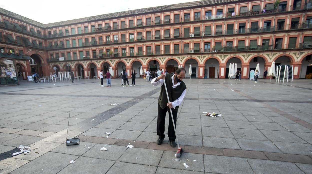 Un camarero barre la zona de terrazas de la Corredera