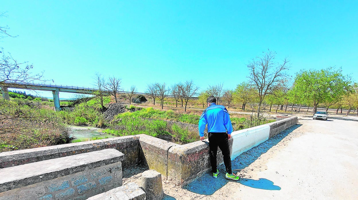 Un hombre mira el caudal del río Cabra desde el puente de Las Salinas