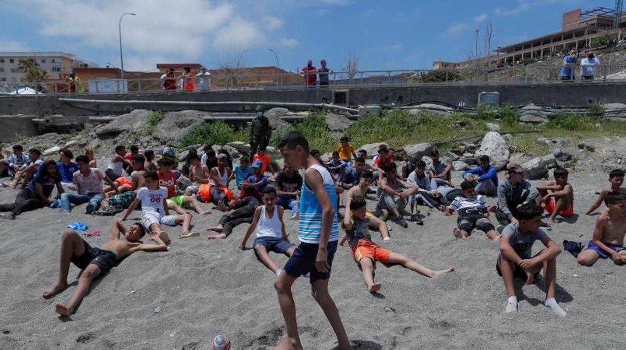 Un grupo de menores espera en una de las dunas de la plaza del Tarajal