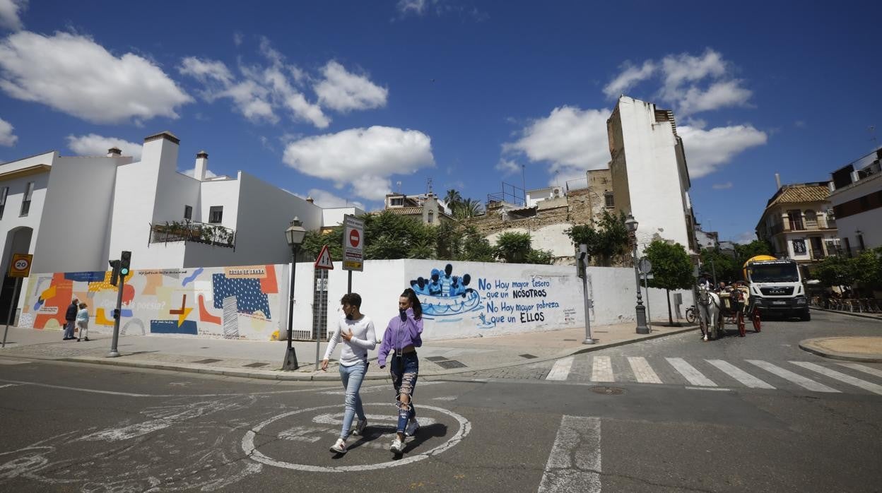 Dos jóvenes pasan delante del solar de la Cruz del Rastro