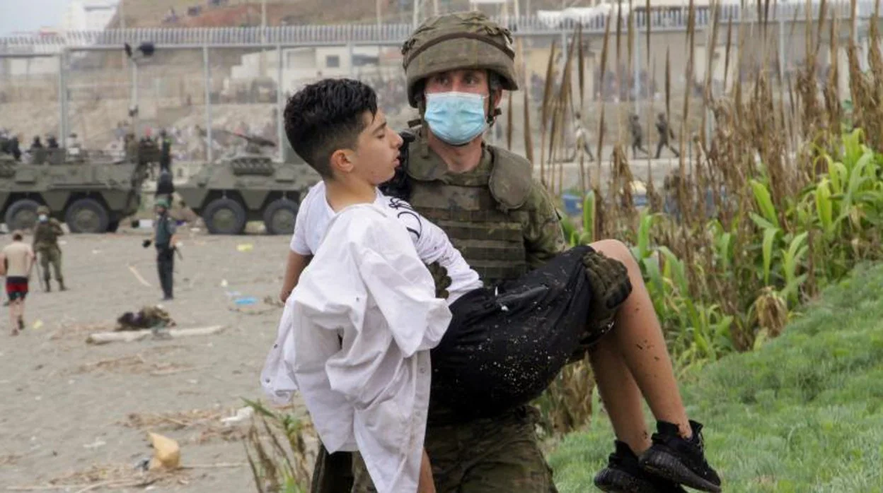 Un soldado español ayuda a un joven inmigrante durante la crisis de frontera en Ceuta