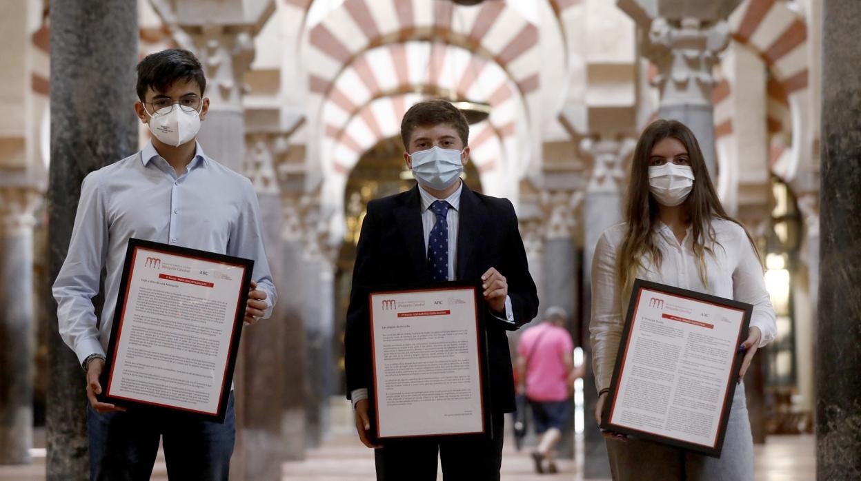 Los tres galardonados en los IV Premios de Narrativa Escolar Mezquita-Catedral posan con sus trabajos en el interior del monumento