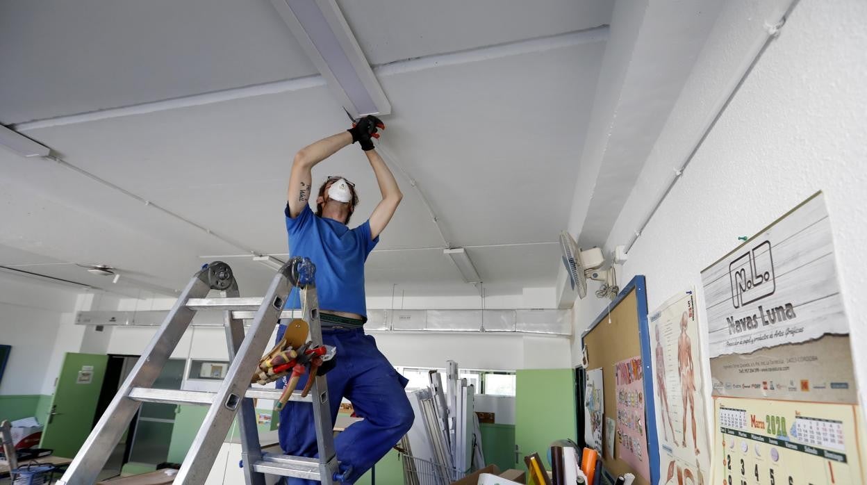 Un operario trabaja en la instalación de un climatizador en un colegio de Córdoba