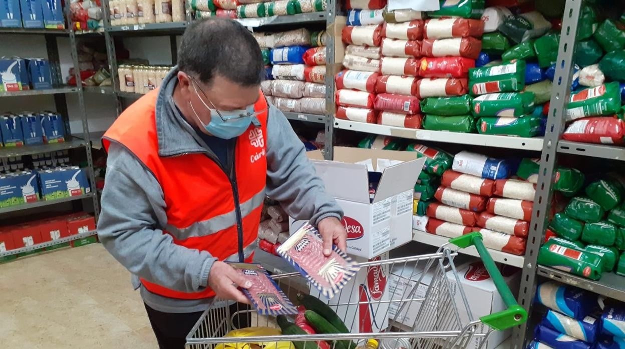 Un voluntario llena un carro en la despensa de Cáritas de Jaén