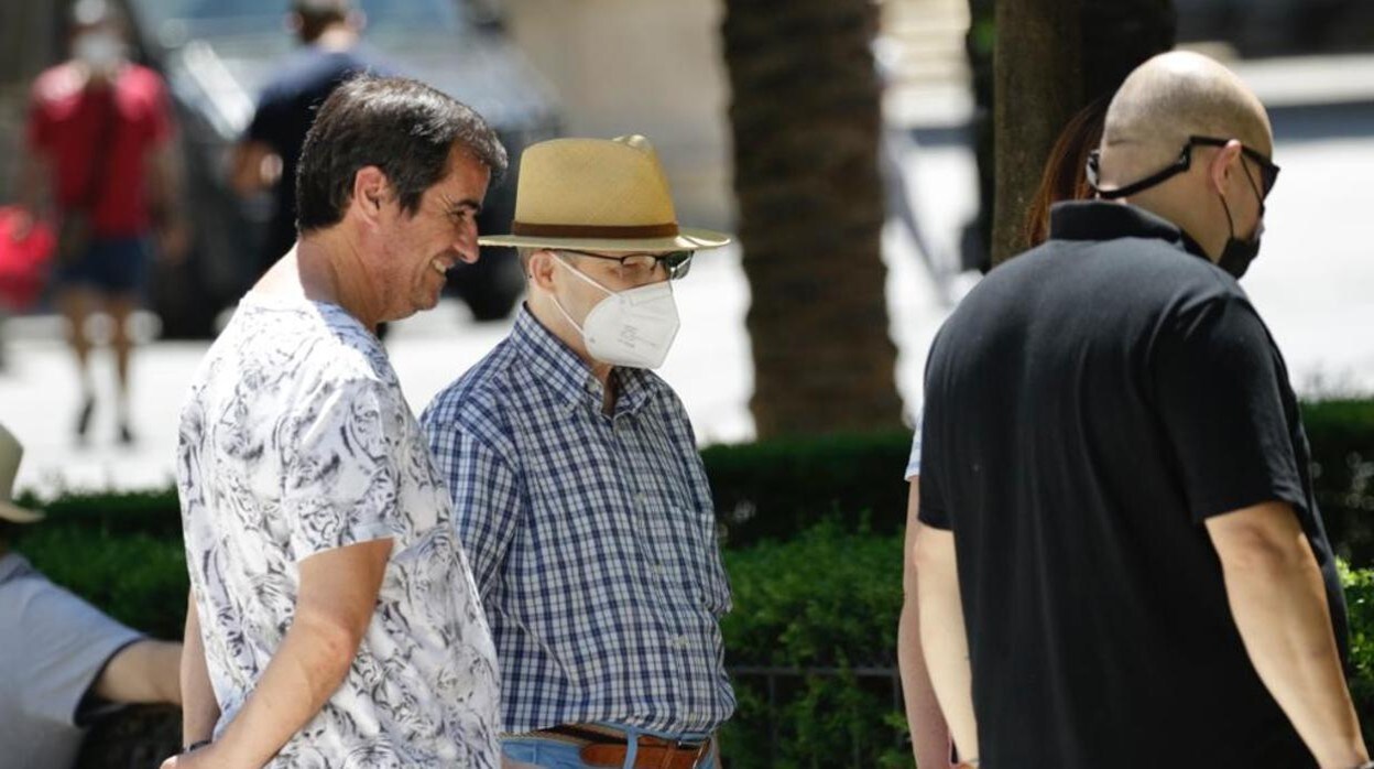 Tres personas, dos con mascarillas, en el centro de Sevilla en la mañana de este sábado