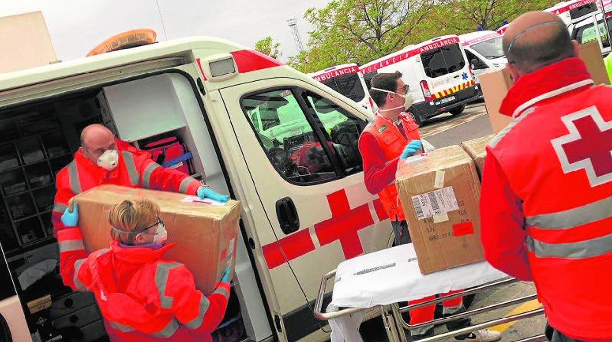 Un equipo de Cruz Roja descarga una ambulancia con material sanitario