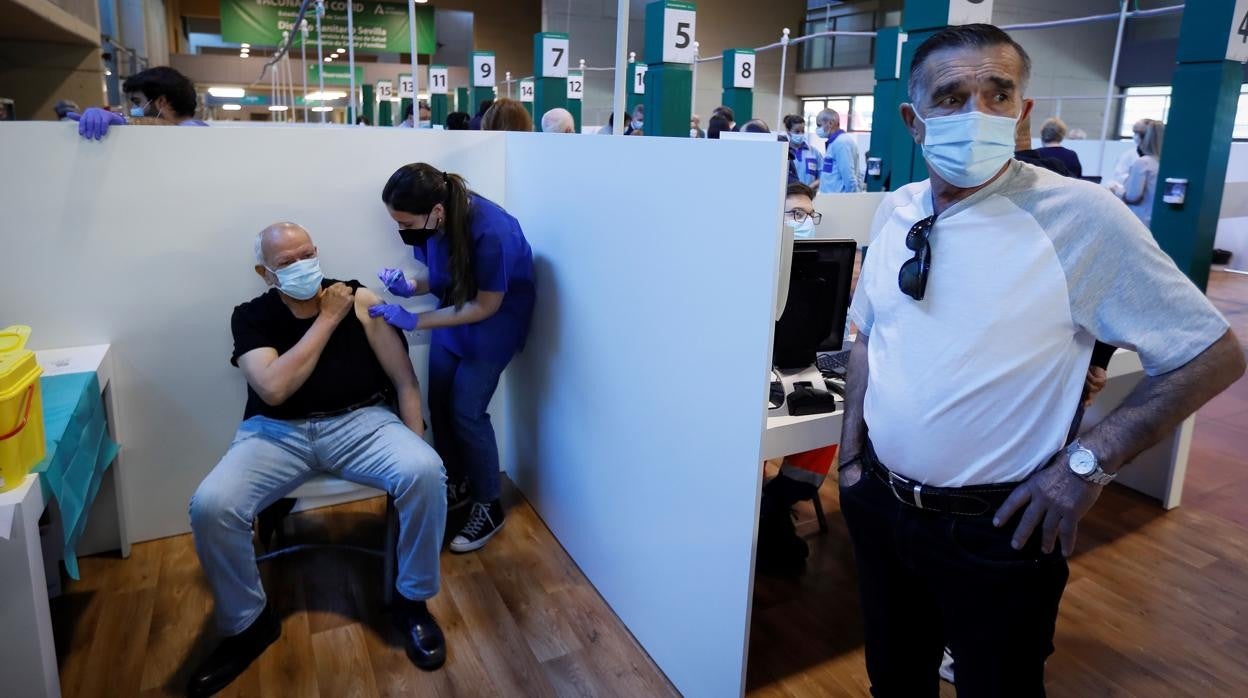 Una sanitaria vacuna a un hombre en el estadio de la Cartuja de Sevilla