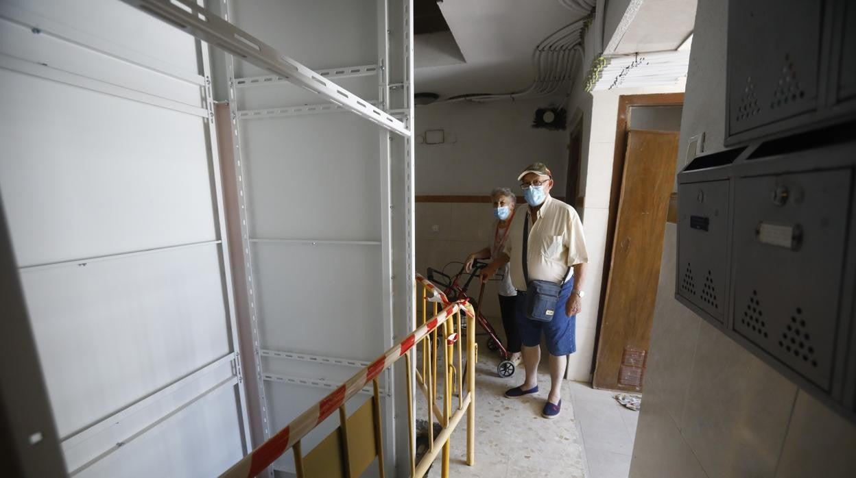 Unos vecinos del Santuario miran la obra de la instalación del ascensor en su edificio