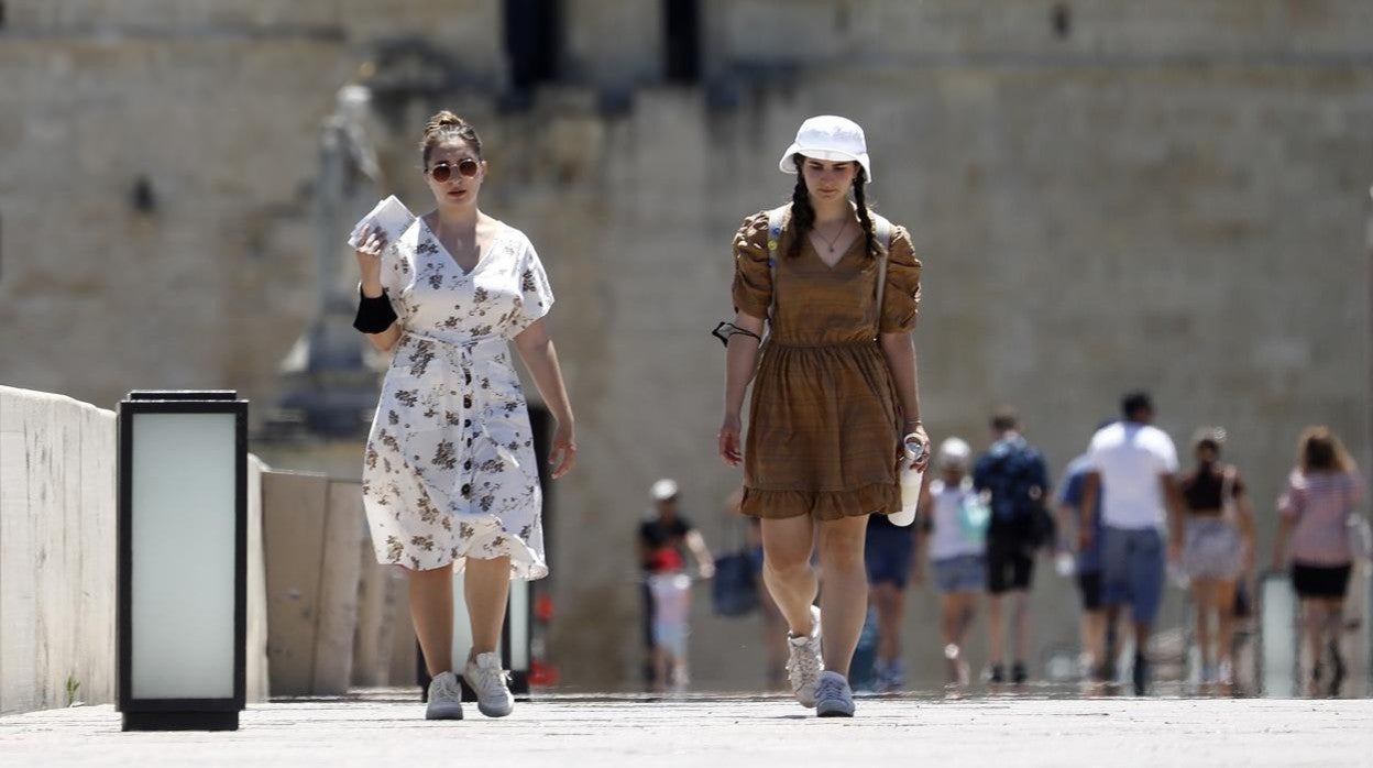 Dos turistas, bajo el calor, en el Puente Romano de Córdoba