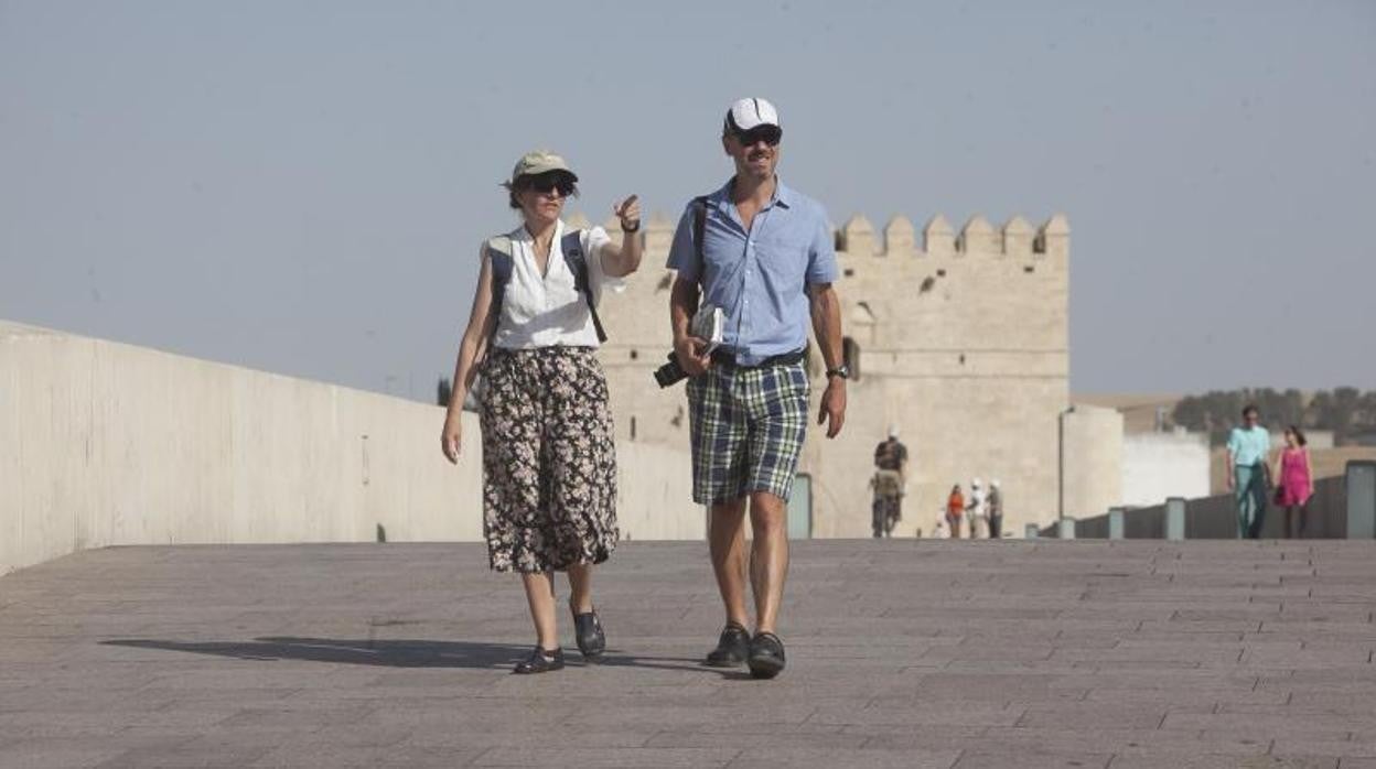 Una pareja pasea por el Puente Romano de Córdoba en verano