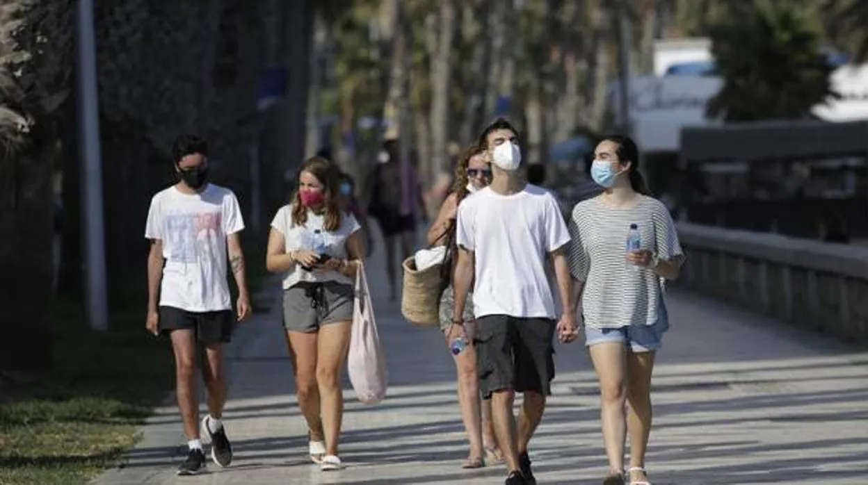 Jóvenes caminan con mascarilla por el Paseo Marítimo Pablo Ruiz Picasso