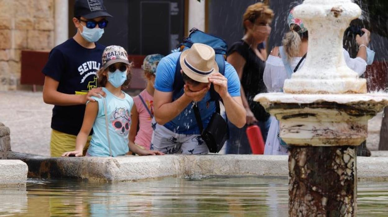 Turistas este martes en Córdoba refrescándose en una fuente