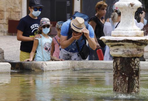 Un grupo de turistas se refresca ayer en la fuente del Patio de los Naranjos