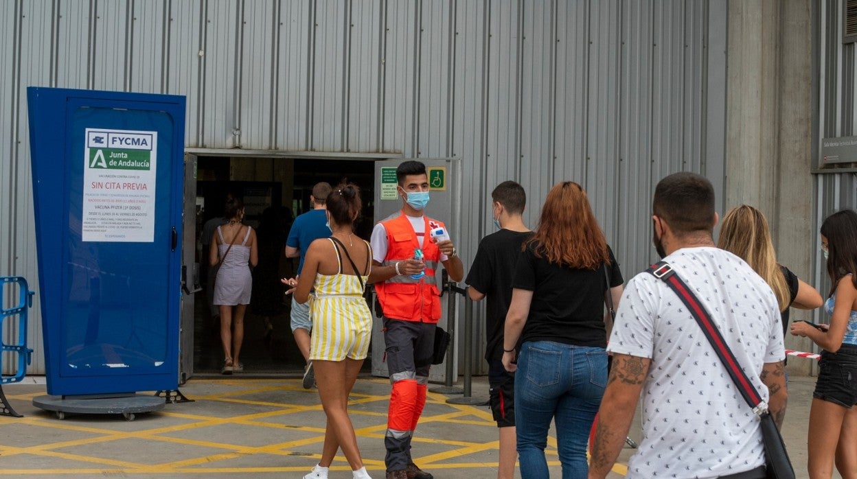 Un voluntario toma la temperatura a quienes acuden a vacunarse en el Palacio de Ferias y Congresos de Málaga