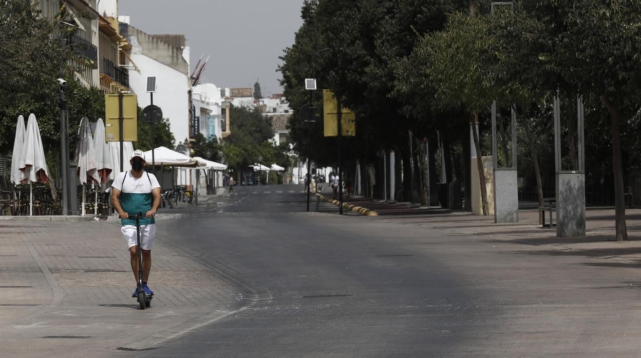 Un hombre pasa en un patinete por la Ribera de Córdoba