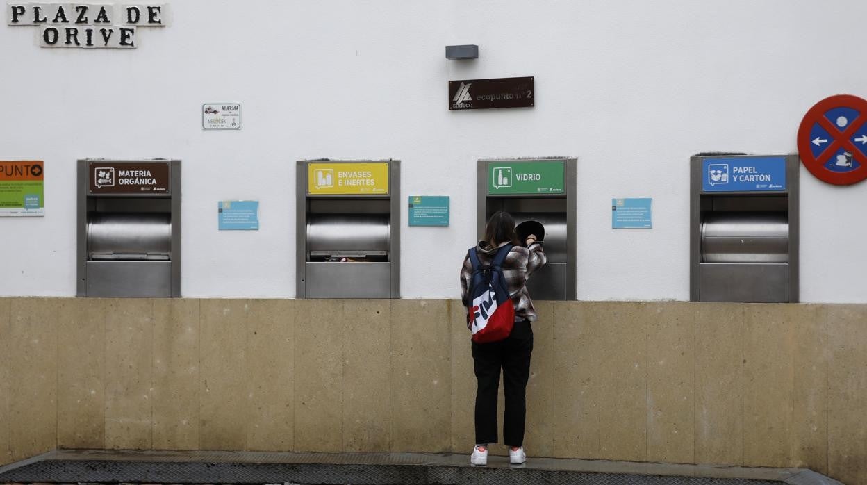 Una joven reciclando vidrio en un punto limpio de Sadeco