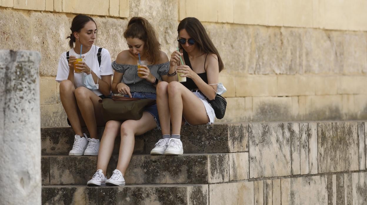 Tres jóvenes, en los graderíos de la Mezquita-Catedral de Córdoba