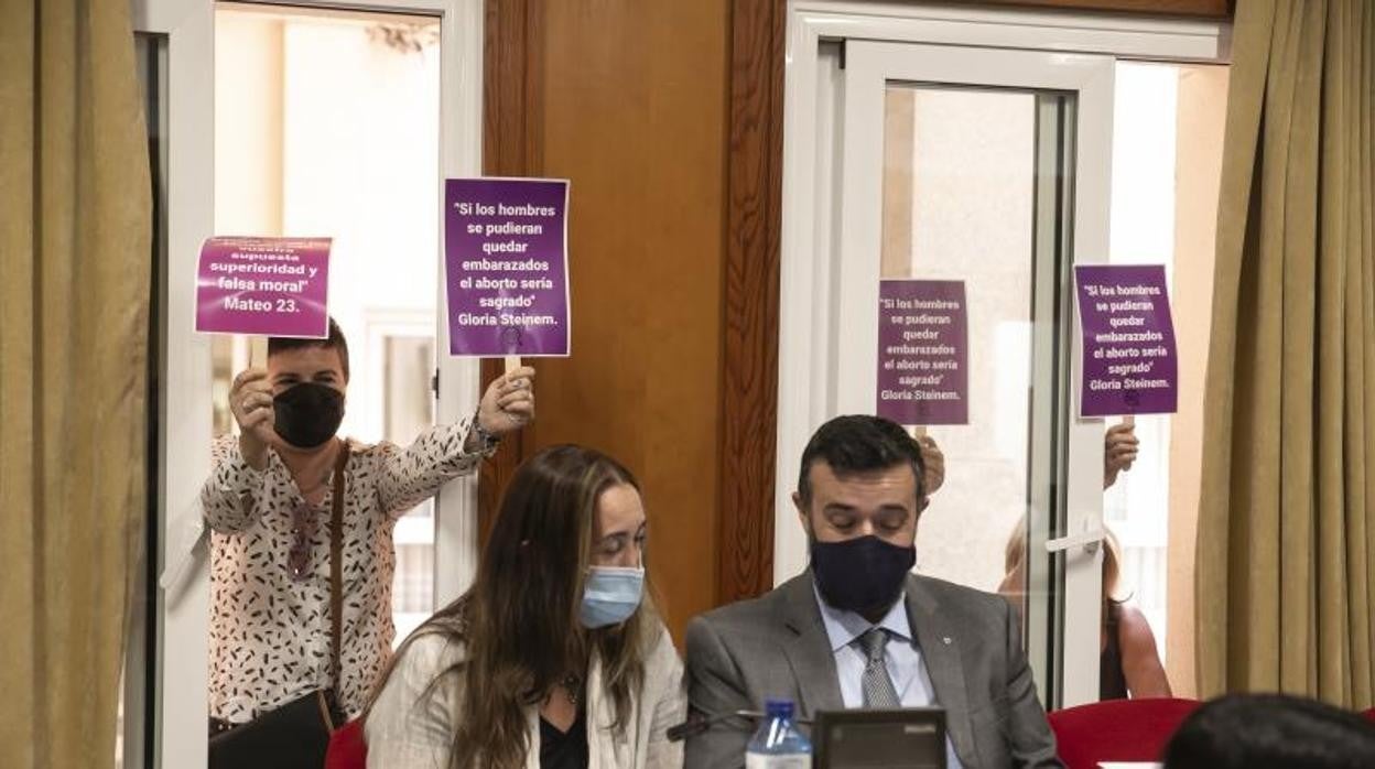 Los concejales de Vox en el último Pleno de Córdoba, con una manifestante detrás a favor del aborto