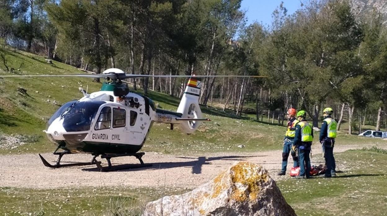 Agentes de la Guardia Civil ante el helicóptero que ayuda en los rescates.