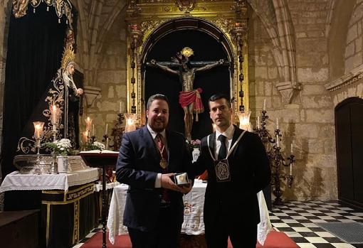 El hermano mayor de Ánimas, José Ignacio Aguilera, entrega al de la Salud, Rafael Cano, un broche como regalo para la bendición