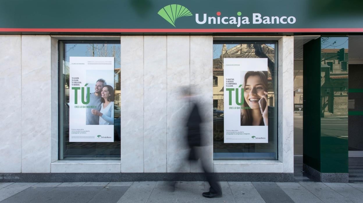 Un viandante camina delante de una sucursal de Unicaja Banco en Córdoba