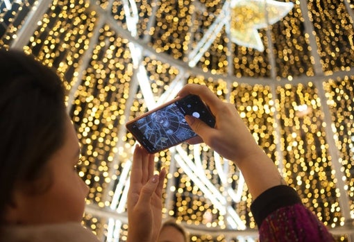 Una chica fotografía el árbol de Navidad instalado en la Plaza de la Constitución de Málaga