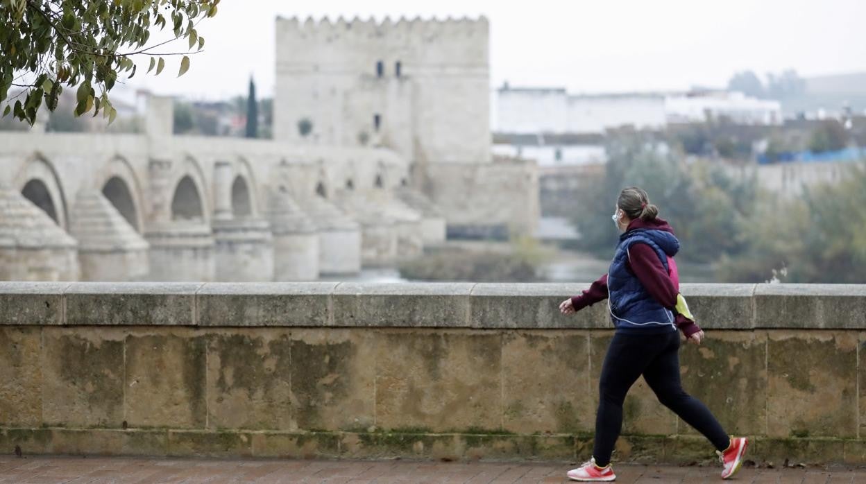 Una mujer pasea junto al Puente Romano de Córdoba