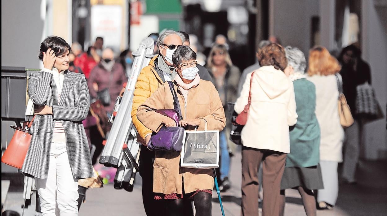 Ciudadanos por la calle, algunos de ellos con mascarilla