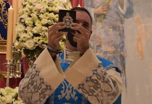 El párroco muestra el broche de los cofrades de la Divina Pastora de Capuchinos