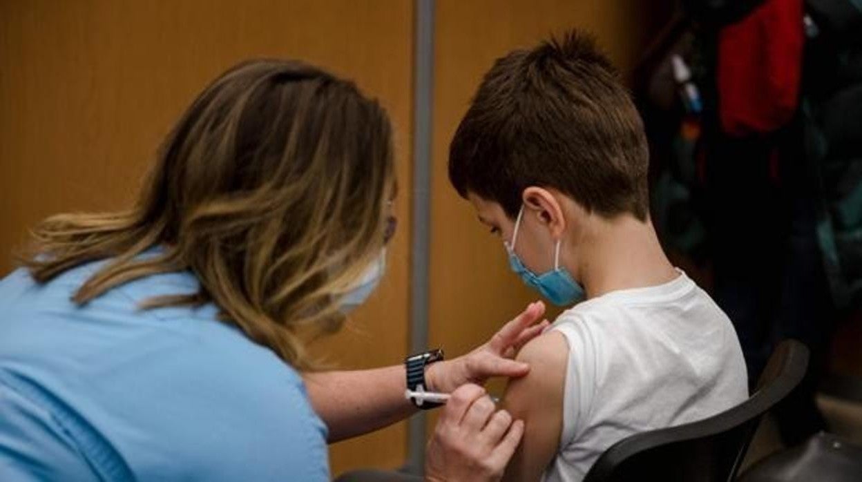 Una sanitaria vacuna a un niño