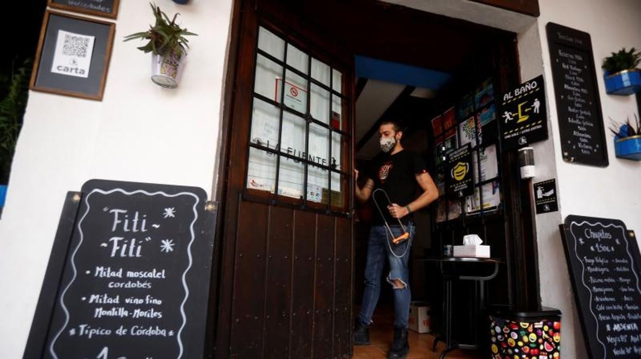 El trabajador de un bar abre las puertas del establecimiento en Córdoba